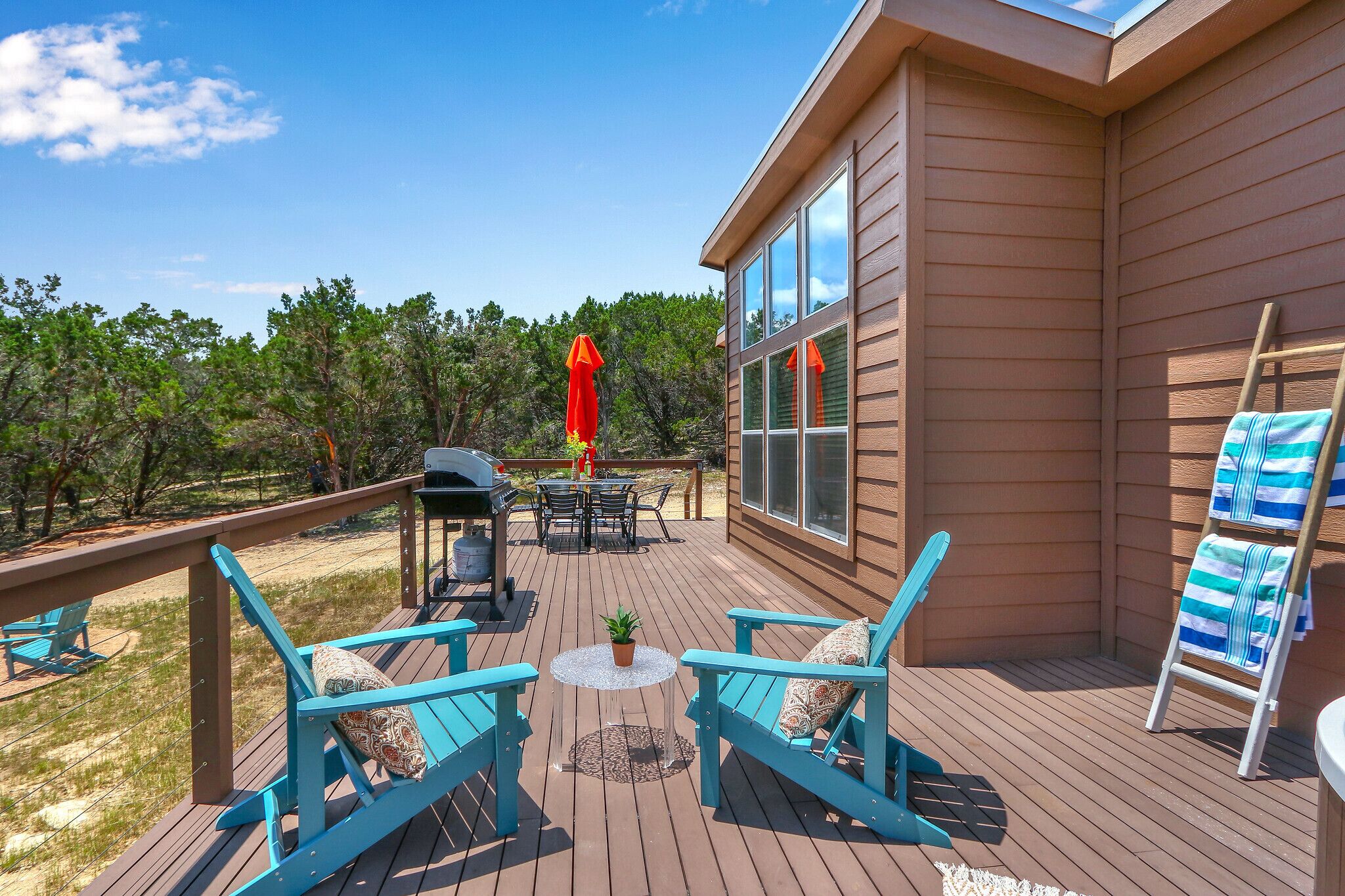 A deck with outdoor furniture, a grill, and a view of the surrounding landscape.