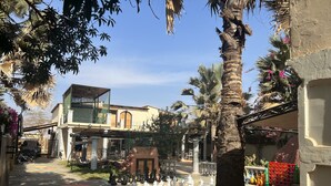 A courtyard with a chessboard, palm trees, and a building with a balcony. - Chez Lilie Maison d'hôtes à Saly (Mbour)