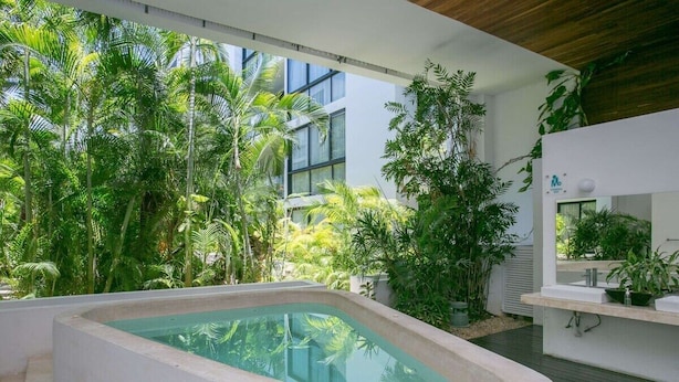 Een modern zwembad met weelderige tropische beplanting, een ingebouwd jacuzzi en een strak design.