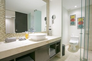 A modern bathroom with a large mirror, a white sink, and a glass shower enclosure.