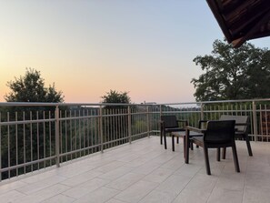 Ein Balkon mit Fliesenboden, Metallgeländer und zwei Stühlen.