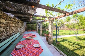 A covered outdoor dining area with a stone wall, wooden benches, and a table set for four. - Pat016 in Pat With 8 Bedrooms and 8 Bathrooms (Patu)