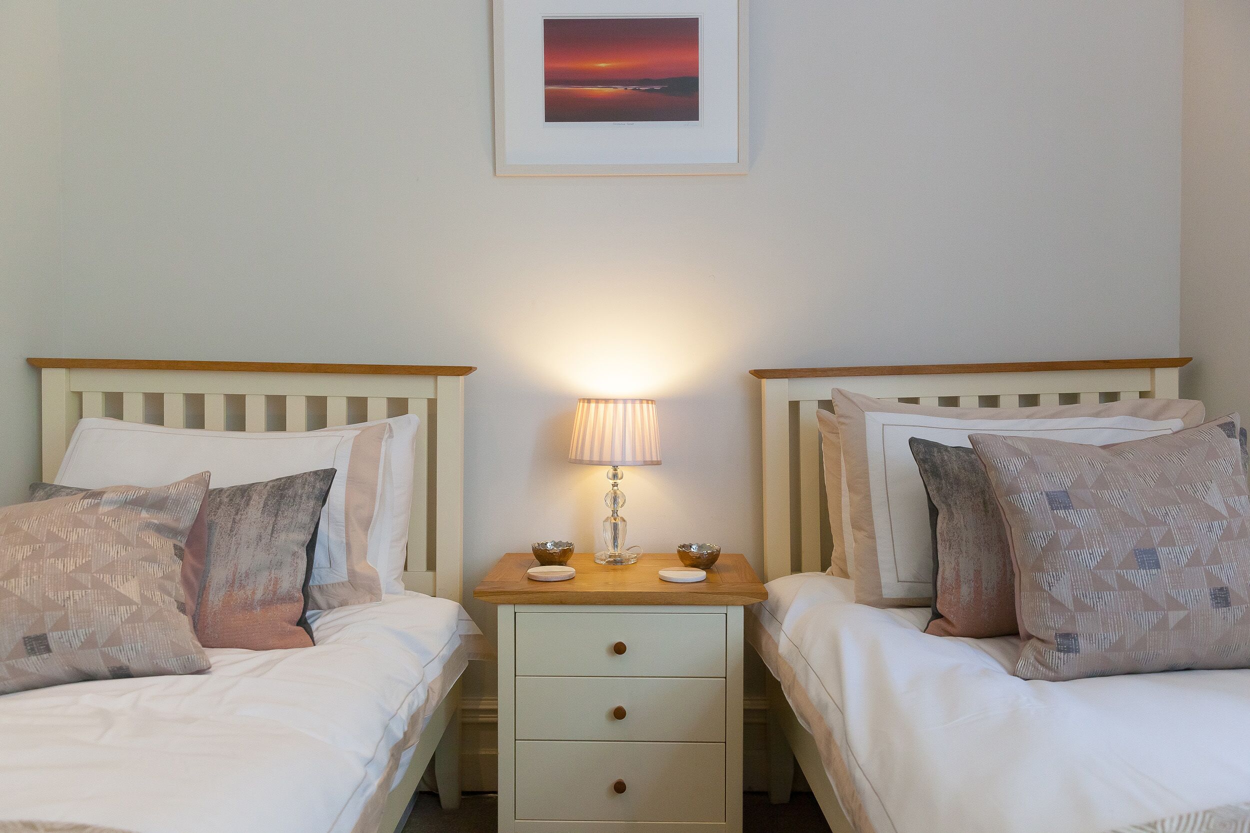 A double bed with a wooden headboard, a bedside table with a lamp, and a framed picture on the wall.