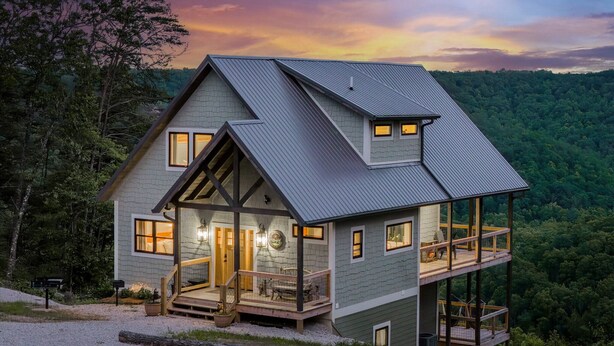 Een twee verdiepingen tellend huis met een balkon, een veranda en uitzicht op het omliggende bos.