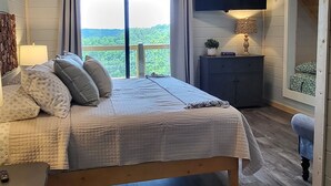 Een slaapkamer met een bed, nachtkastje, lamp en een televisie.