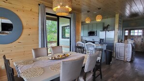 Een houten interieur met een eetgedeelte, inclusief een ronde spiegel, een tafel met placemats en uitzicht op de omgeving.