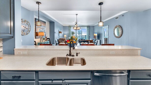 A modern kitchen with a large island, double sink, and pendant lighting.