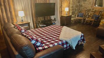 Une pièce confortable avec un grand lit, un canapé en cuir, une télévision et une cheminée.
