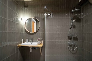 A bathroom with a sink, mirror, and shower. - Paorra Baserria (Aia)