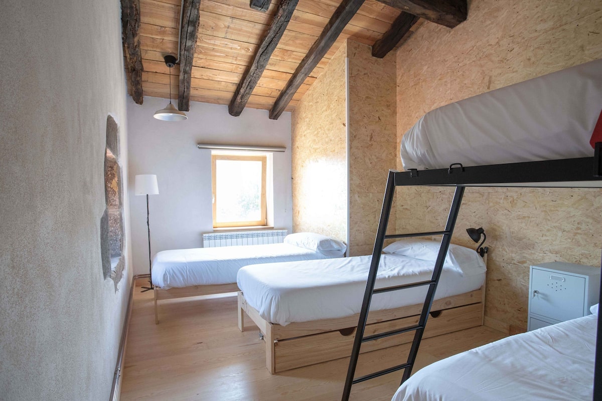 A dormitory room with bunk beds, a window, and a radiator.