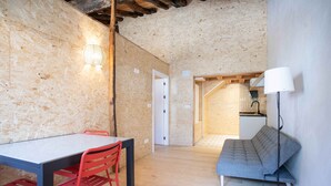 A room with a wooden floor, a dining table with chairs, a sofa, and a lamp. - Paorra Baserria (Aia)
