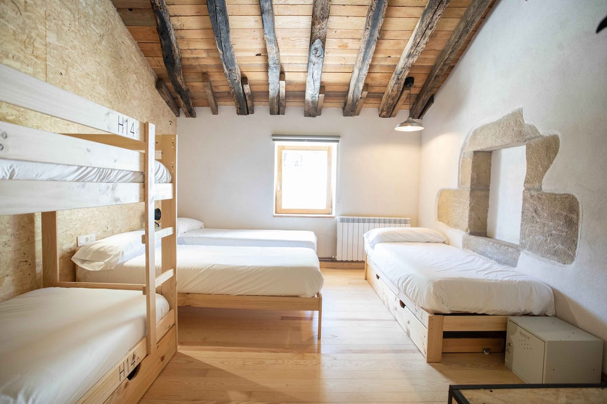 A room with bunk beds, a window, and a stone wall.