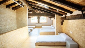 A wooden interior with bunk beds arranged in a row, a window with a view, and a radiator on the wall. - Paorra Baserria (Aia)