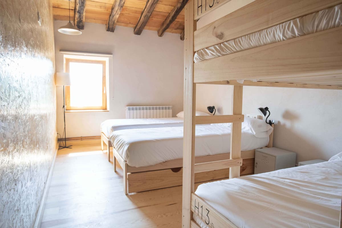 A bunk bed room with a wooden ceiling, a radiator, and a window.