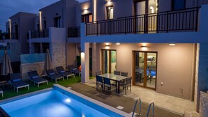 Un edificio moderno de dos pisos con piscina, mobiliario exterior y zona de comedor.