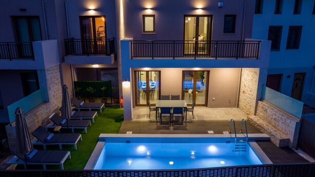 Un edificio moderno de dos pisos con piscina, mobiliario exterior y un balcón.