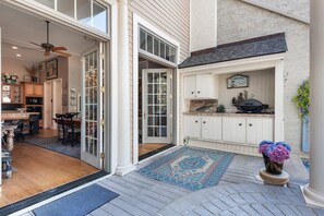 A spacious kitchen with a large island, a dining area with a wooden table and chairs, and a view of the backyard through a sliding glass door. - 8 Mizzenmast Court at The Sea Pines Resort (Hilton Head Island)