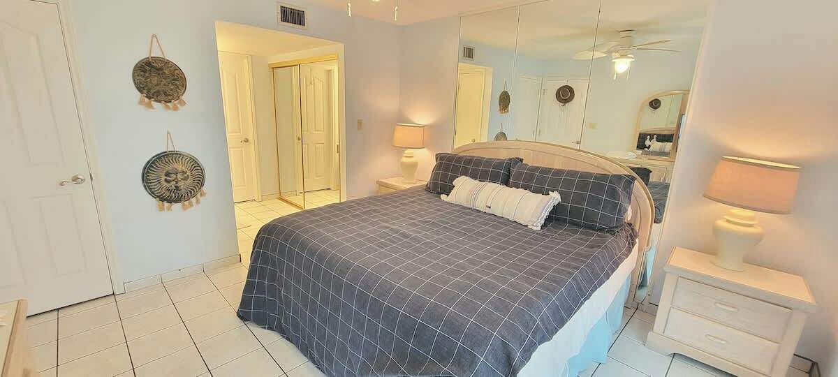 Un dormitorio con cama, mesitas de noche, un espejo y una puerta.