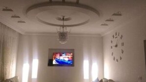 Een woonkamer met een televisie, een klok en een kroonluchter.