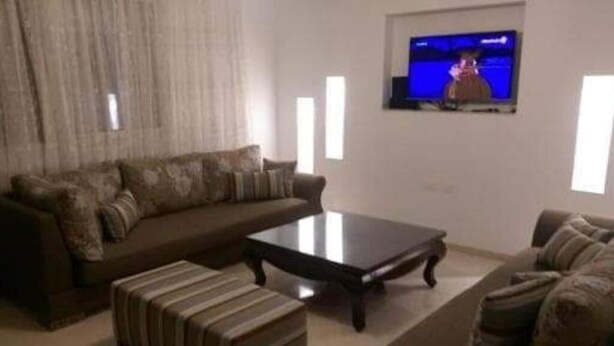Een woonkamer met een bank, een salontafel en een televisie aan de muur.
