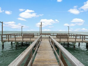 A wooden pier extending into calm waters with a clear sky above. - Sailing Windward by Miss Kitty’s (Rockport)