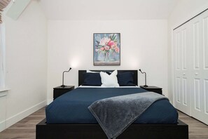 Un dormitorio con una cama grande, dos mesitas de noche, un cuadro en la pared y un armario.