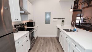 Een moderne keuken met witte kasten, roestvrijstalen apparatuur en een houten vloer.