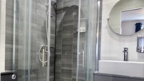 A modern bathroom with a glass-enclosed shower, a white toilet, and a dark-toned vanity with a mirror. - blackpools (Thornton Cleveleys, Blackpool)