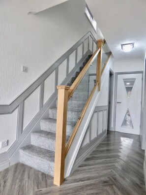 Staircase leads to a landing with a door featuring a geometric glass design.
