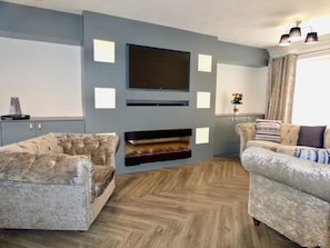 Relax in this stylish living room with a large flat-screen TV, fireplace, and plush sofas.