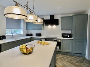 Enjoy cooking in this well-equipped kitchen with a large island, microwave, and sleek range hood.