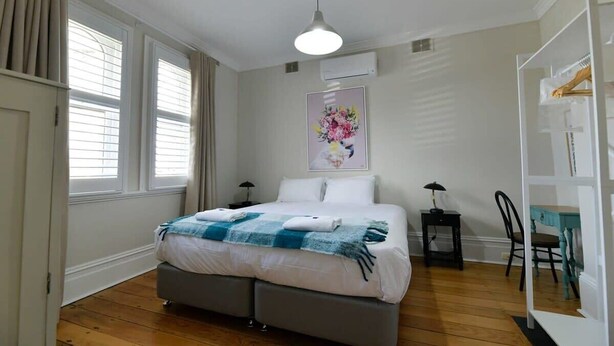 A bedroom with a bed, bedside tables, a chair, a desk, and a wardrobe.