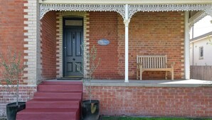 A brick building with a porch, a door, and a bench.