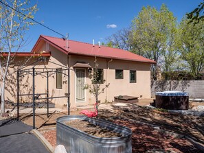 A single-story house with a red roof, a small porch, and a hot tub in the backyard. - Casa Lujan by Kokopelli Property Management (Santa Fe)