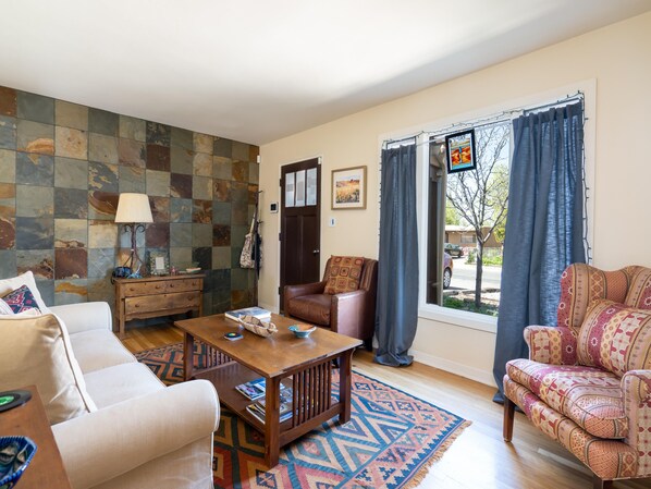 A living room with a sofa, armchair, wooden coffee table, and a patterned rug. - Casa Lujan by Kokopelli Property Management (Santa Fe)
