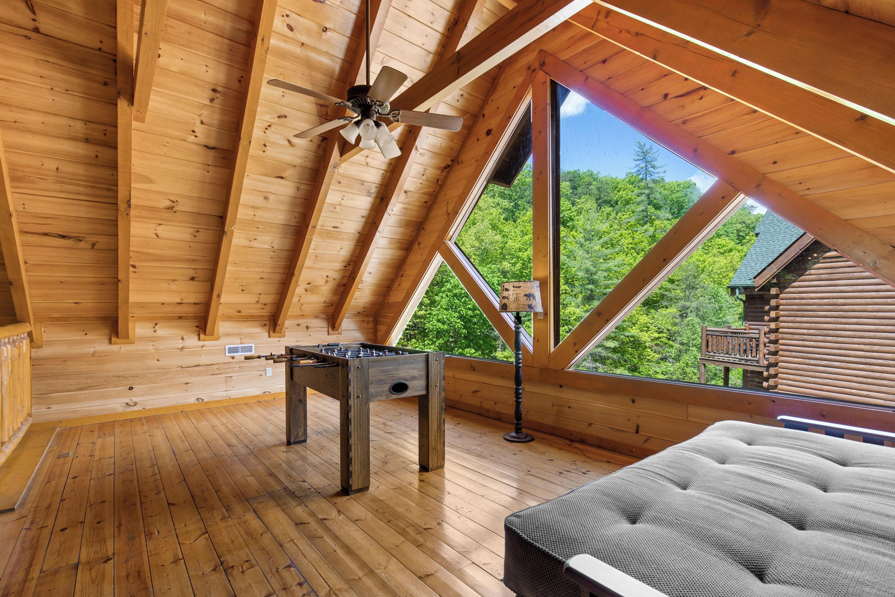 Ein Schlafzimmer im Blockhaus-Stil mit Schlafgalerie, Deckenventilator, Futonbett und Kicker.