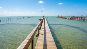 Un muelle de madera que se adentra en aguas tranquilas bajo un cielo despejado.