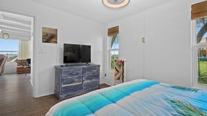 A bedroom with a bed, a dresser, a television, and a window with a view of the outdoors. - Little Cove Resort by Miss Kitty’s (Taft)