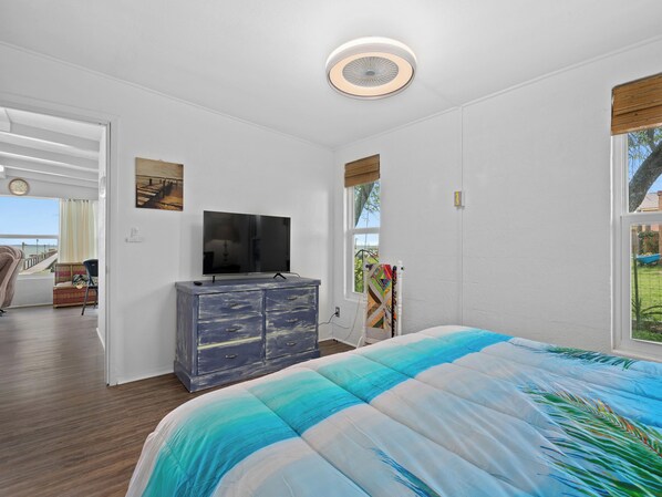 A bedroom with a bed, a dresser, a television, and a window with a view of the outdoors. - Little Cove Resort by Miss Kitty’s (Taft)