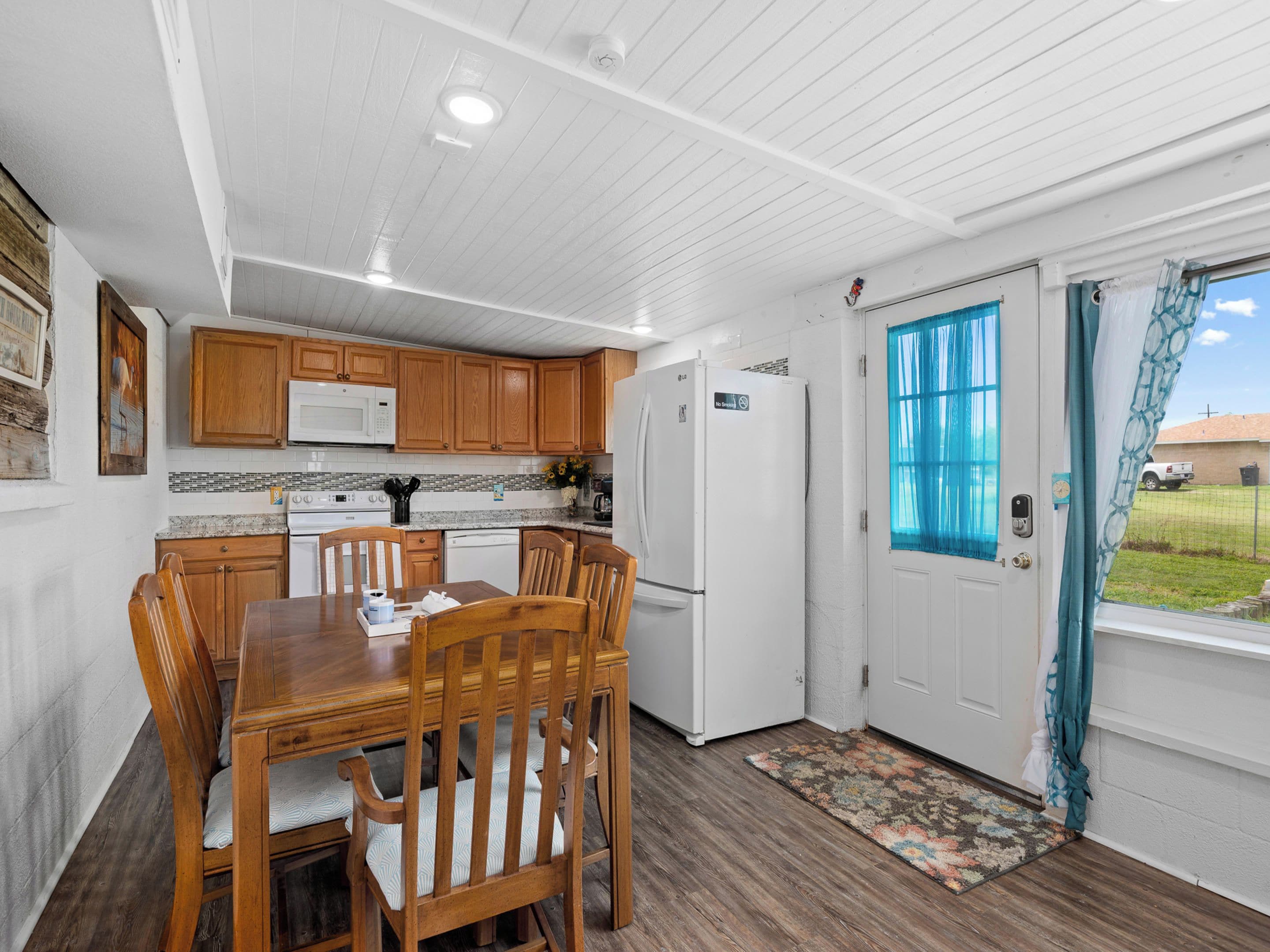 A kitchen with wooden cabinets, a white refrigerator, and a dining table with chairs.