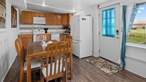A kitchen with wooden cabinets, a white refrigerator, and a dining table with chairs. - Little Cove Resort by Miss Kitty’s (Taft)