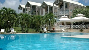 Un hotel con piscina, sombrillas blancas y palmeras.