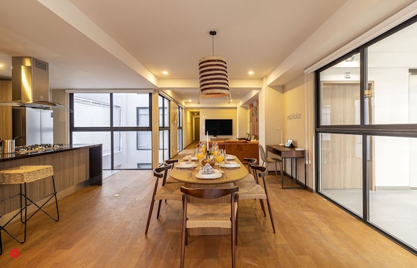Enjoy meals in this stylish dining area with a long table, pendant light, and large window.