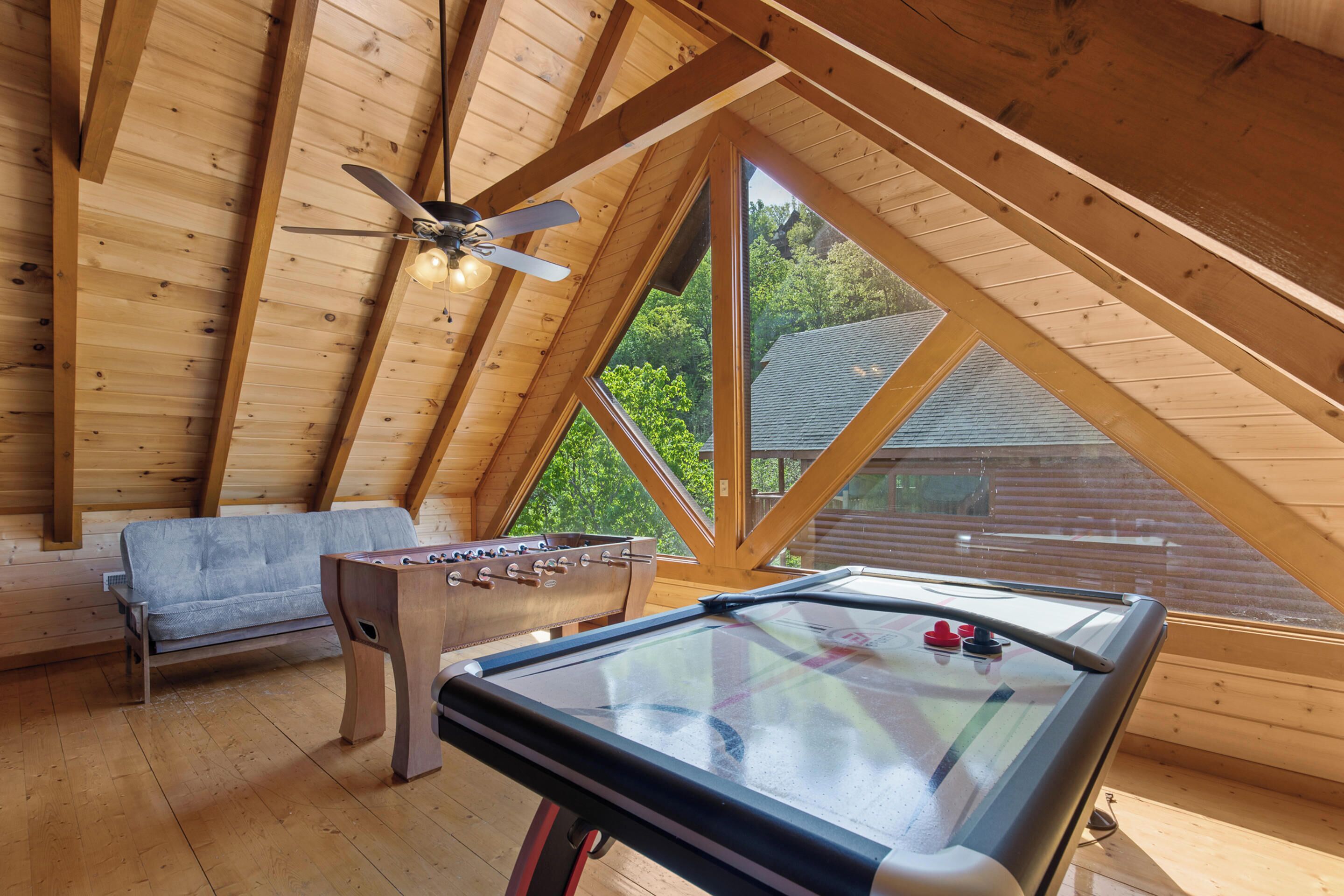 A cozy room with a foosball table, a sofa, and a ping pong table.