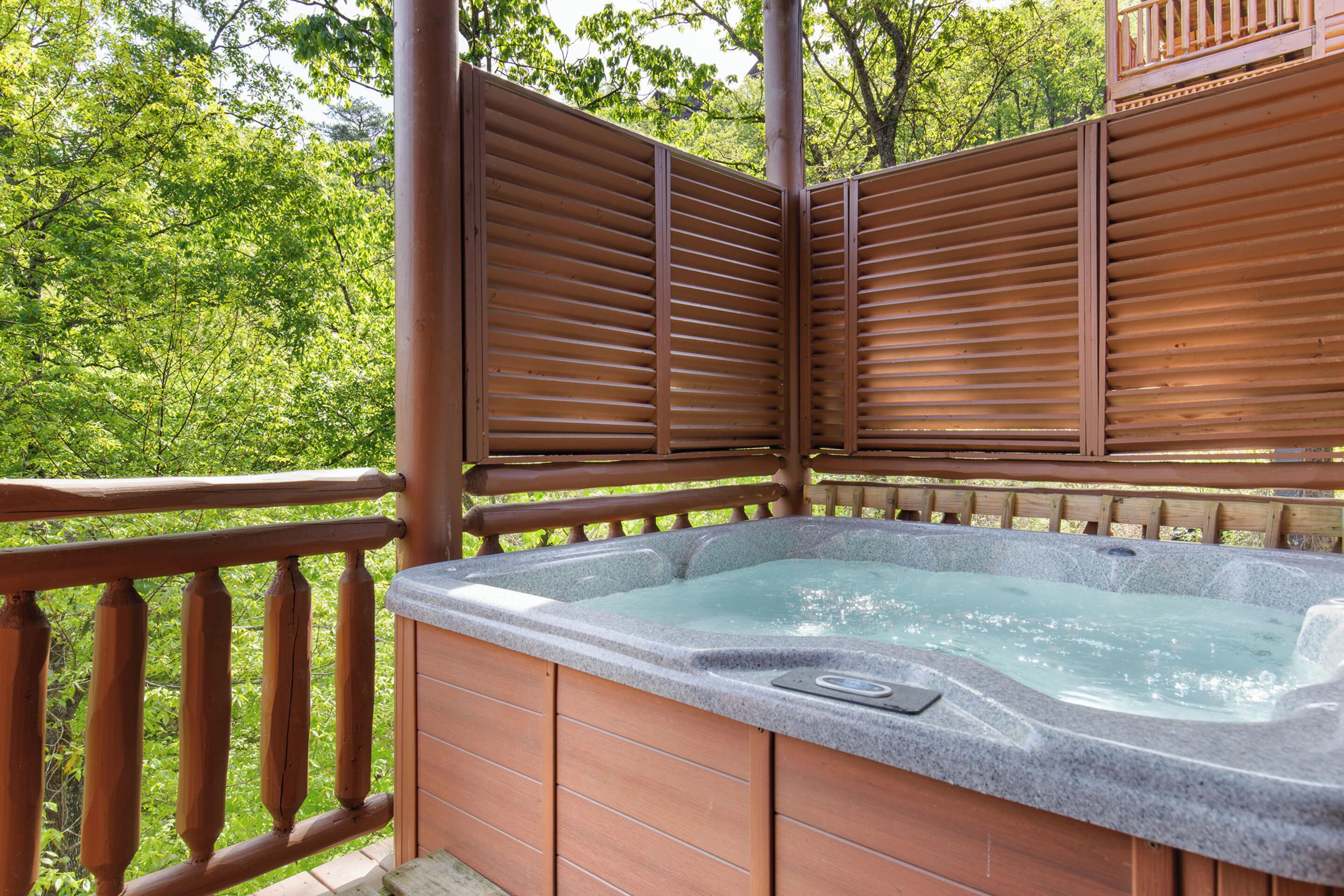 A hot tub on a wooden deck with a view of green trees.
