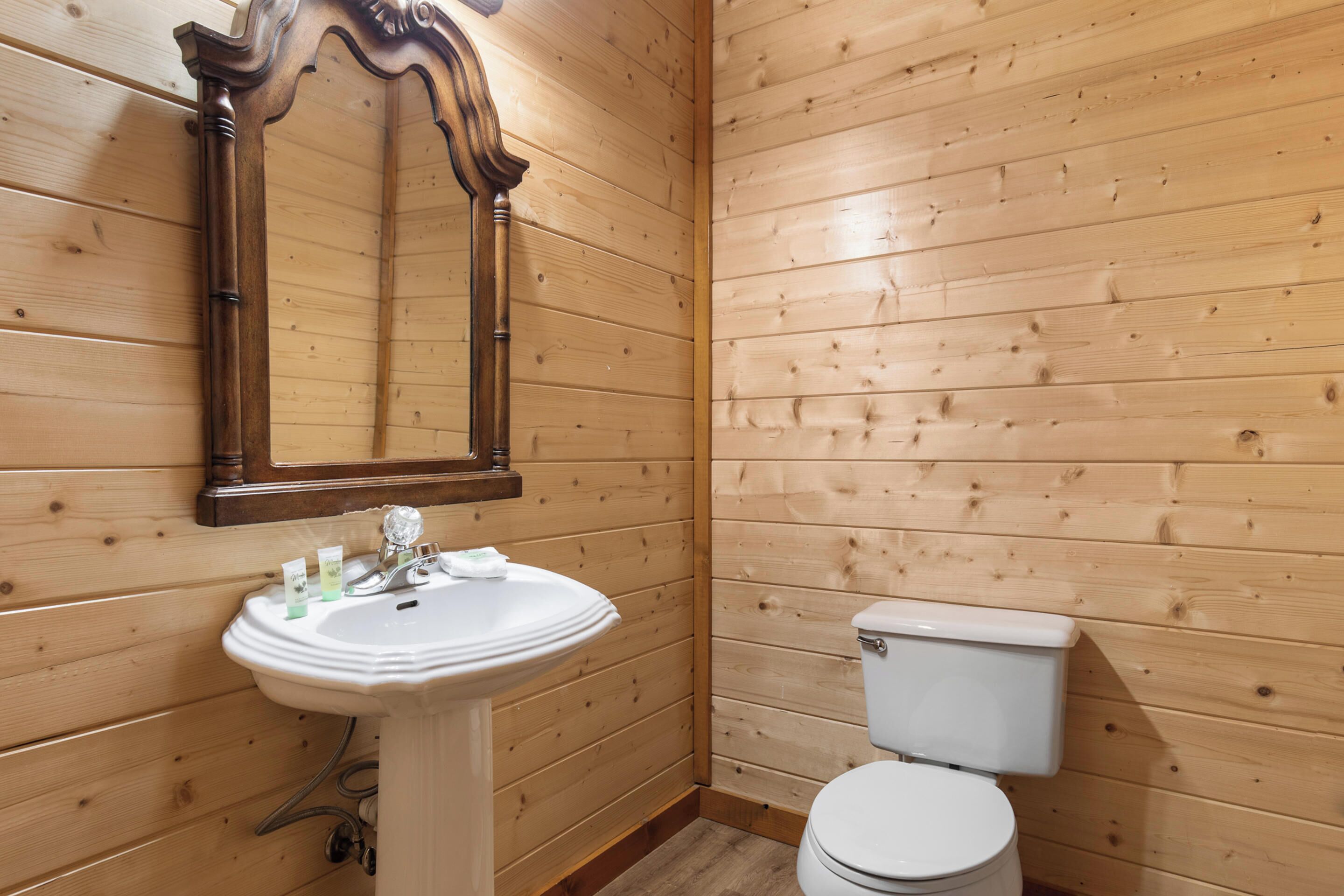 A wooden-paneled bathroom with a white sink and a toilet.
