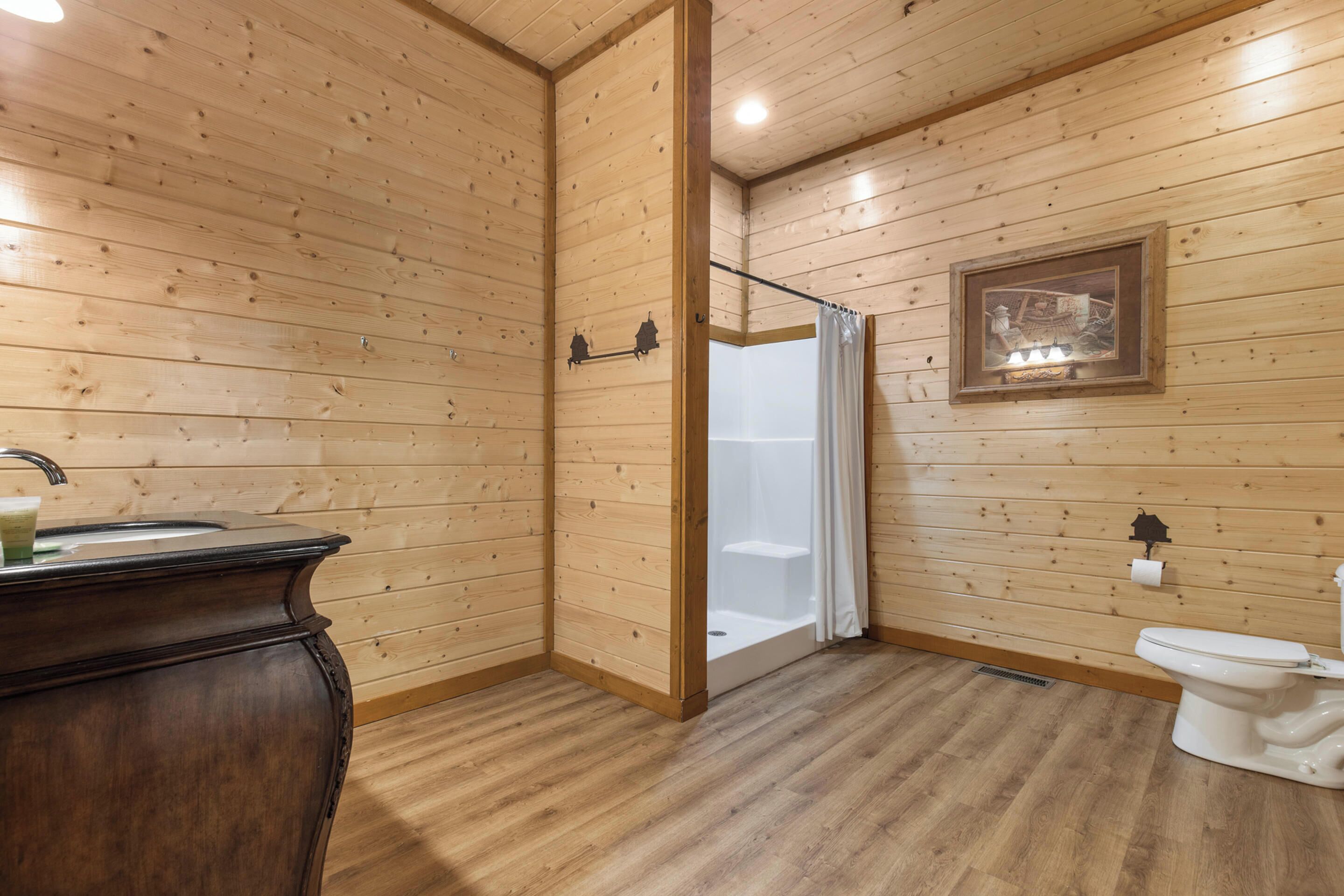 A wooden-paneled bathroom with a sink, toilet, and shower.