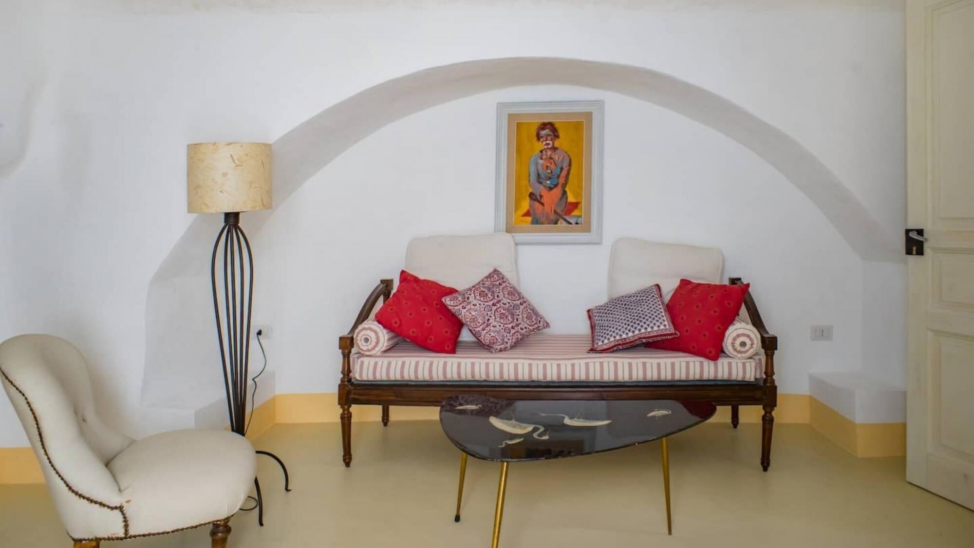 Une pièce comprenant un canapé, un fauteuil, une lampe et un tableau accroché au mur.