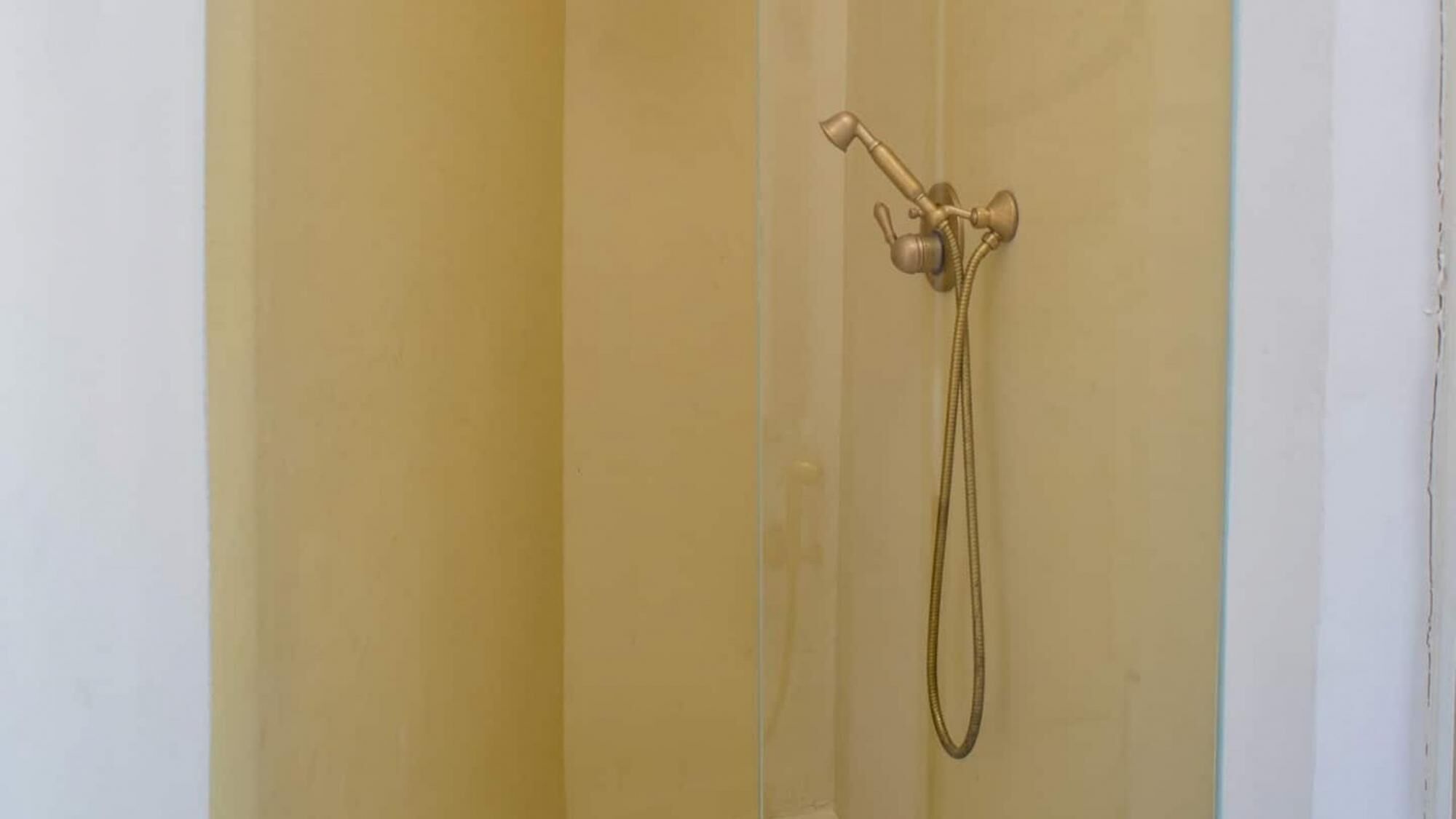 A shower with a handheld showerhead mounted on the wall.
