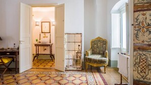 A room with a patterned floor, a chair, a mirror, and a door leading to another room. - Leu075 in Castrignano del Capo (Castrignano del Capo)